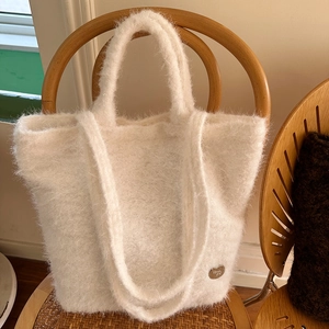 Detailed shot of white plush tote bag with soft faux fur texture and metal logo