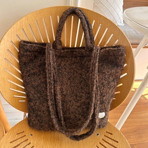 Detail of plush coffee brown tote bag featuring fuzzy texture and silver heart charm