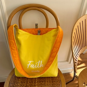 Detail of color-block tote bag with Faith embroidery and orange quilted lining