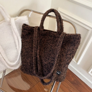 Detail view of plush lamb wool tote bags in brown and beige with dual strap handles