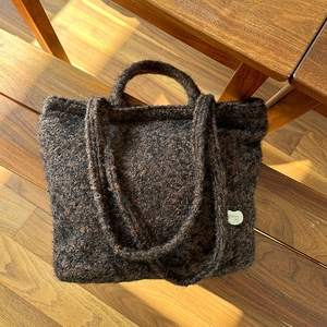 Close-up of the fluffy texture and dual straps on this coffee brown plush tote bag