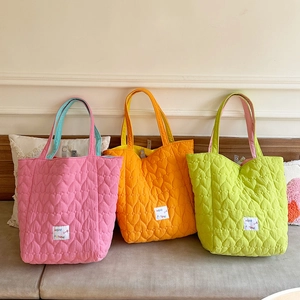 Detail of candy-colored quilted tote bags with heart stitching and contrast lining