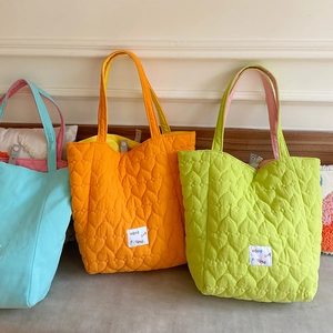 Detail of colorful quilted tote bags with heart pattern and HOPE label embroidery