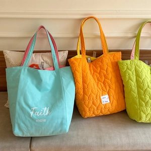Detailed view of candy-colored quilted tote bags with heart patterns and strap details
