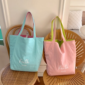 Close-up of contrast color canvas tote bags with Faith mole print on wooden chairs
