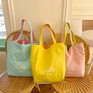 Close-up of quilted canvas tote bags in mint green, yellow, and pink colors on a wooden chair