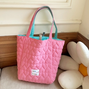 Detail of pink heart-quilted tote bag with blue contrast lining and magnetic closure
