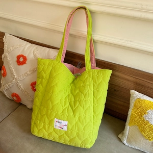 Detail of green heart quilted tote bag with pink lining and embroidered hope text label