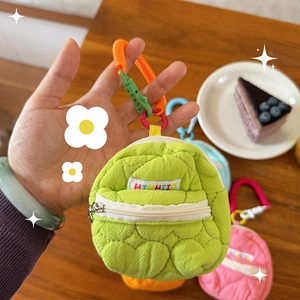 Dettaglio del mini portamonete a zaino verde con trapuntatura a cuore e cordino a molla