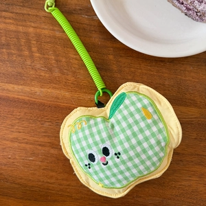 Detail of green plaid apple-shaped earphone pouch with cute embroidery on wooden desk