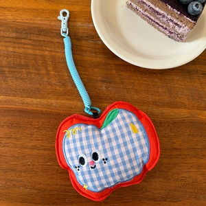 Detail of red apple plush earphone pouch with blue checkered embroidery on wood background