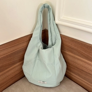 Detailed view of pale green vertical pleated texture and fabric label on a casual bag