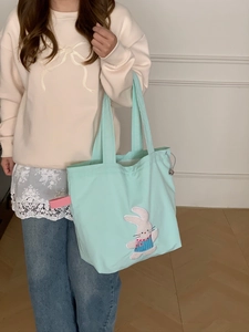 Detail of mint green canvas tote bag with cute rabbit embroidery and side drawstring
