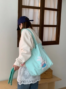 Detailed side view of light blue canvas tote with cute white rabbit embroidery on shoulder