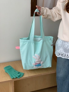 Detail of mint green tote bag with cute bunny embroidery and functional drawstring closure