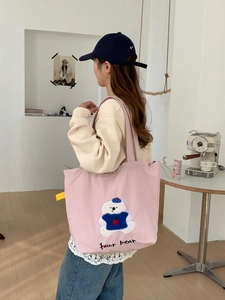 Detail of pink canvas tote bag with embroidered cartoon bear and four bear text