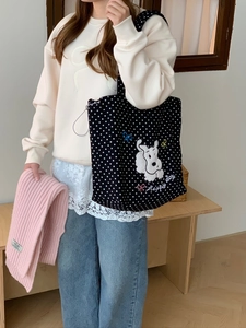 Detail of embroidered dog pattern and Happy Day text on a polka dot canvas tote bag