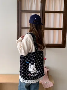 Lifestyle shot of black polka dot canvas tote bag with embroidered puppy and Happy day text