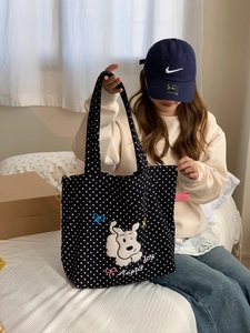 Detail view of cartoon dog embroidery and Happy Day lettering on black polka dot canvas tote