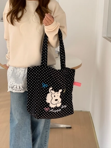Detail of black canvas tote bag with white polka dots and embroidered cartoon dog patch