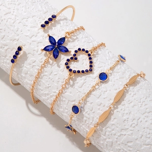 Détail d'un lot de 5 bracelets dorés avec cristaux bleus sur support blanc