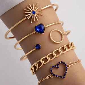 Détail d'un ensemble de 6 bijoux dorés et papillon bleu portés sur un poignet