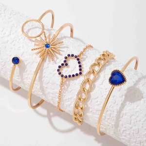 Détail de cinq bracelets dorés avec strass bleus et motifs ajourés en coffret cadeau
