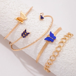 Macro détaillée d'un ensemble de 5 bracelets dorés avec papillons bleus et cristaux