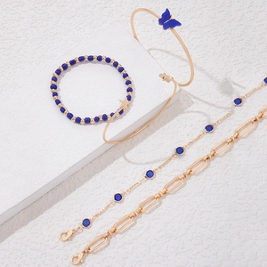 Détail d'un ensemble de cinq bracelets dorés avec papillons bleus et pierres serties