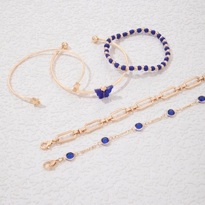 Détail d'un ensemble de cinq bracelets or et bleu avec breloques papillon et étoile