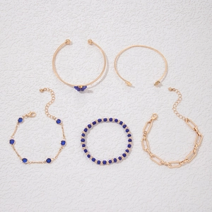 Détail d'un ensemble de 5 bracelets dorés avec papillon bleu et charmes en strass