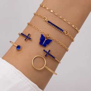 Détail d'un ensemble de cinq bracelets dorés avec breloques papillon bleu et strass
