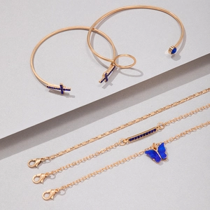 Détail d'un ensemble de cinq bracelets dorés avec breloques papillon bleues et cristaux