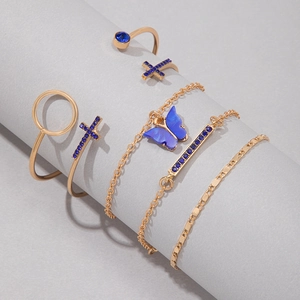 Détail d'un ensemble de bracelets dorés avec cristaux bleus sur un support gris