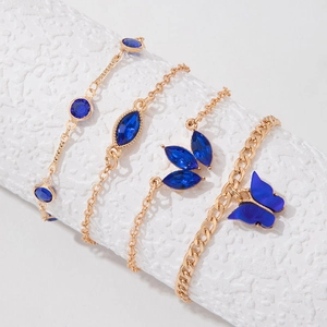 Détail d'un ensemble de 4 bracelets dorés avec breloques papillon bleu et pierres précieuses