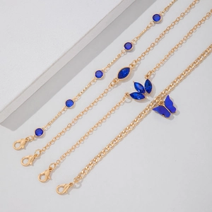 Détail d'un ensemble de quatre bracelets dorés avec breloques papillon bleues et gemmes