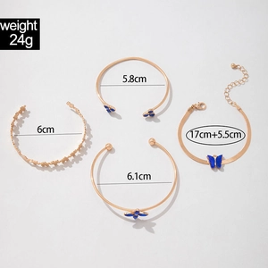 Vue détaillée d'un ensemble de quatre bracelets dorés avec papillon bleu et trèfles