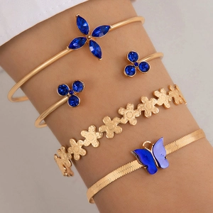 Détail d'un ensemble de quatre bracelets dorés avec papillon bleu et charmes de fleurs