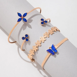 Détail du set de 4 bracelets dorés avec fleurs en cristal bleu et pendentifs papillon