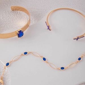 Détail d'un ensemble de bijoux dorés avec pierres bleues et design papillon ajouré
