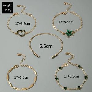 Détail d'un ensemble de cinq bracelets dorés avec breloques en cristal vert et cœur