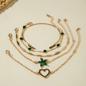 Détail d'un ensemble de cinq bracelets dorés avec pierres émeraude et breloques cœur