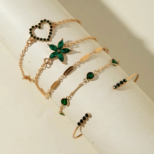 Détail d'un ensemble de 5 bracelets dorés avec pierres vertes sur pilier blanc
