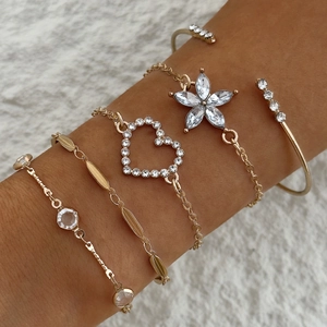 Gros plan sur un ensemble de bracelets dorés avec breloques fleurs et cœurs