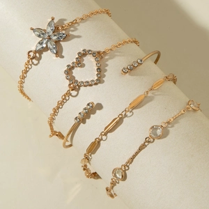 Détail d'un ensemble de 5 bracelets dorés avec papillon bleu et cristaux sur support