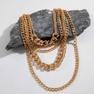 Detail of layered gold chain necklace featuring thick Cuban and thin link textures