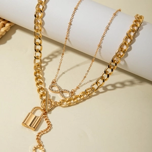 Close-up of golden chunky chain necklace with heart lock pendant and infinity symbol detail