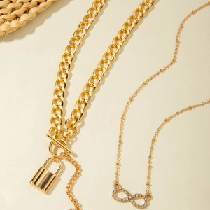 Detail of gold OT buckle lock necklace and infinity symbol pendant with white rhinestones