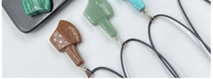Macro shot of stone axe-shaped pendants in malachite, aventurine and goldstone textures