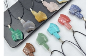 Macro shot of assorted gemstone ax-shaped pendants including rose quartz and agate stones